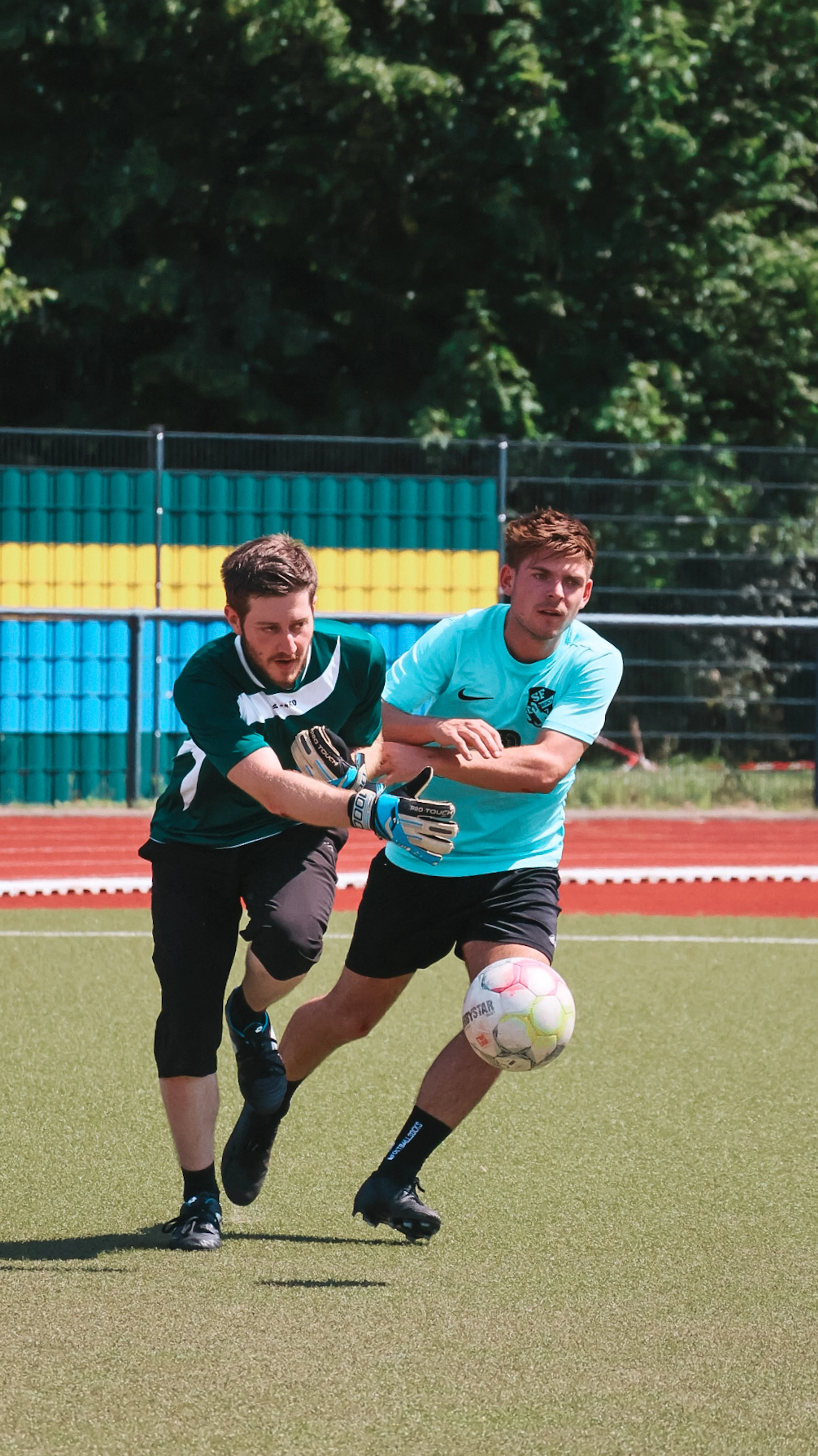 Zwei junge Männer im sportlichen Zweikampf beim Fußballspielen auf einem Kunstrasenplatz.